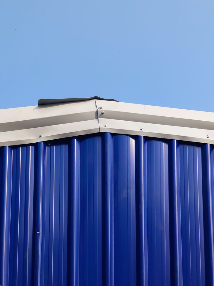 A detailed image of the roof edge of a blue metal building against a clear sky.